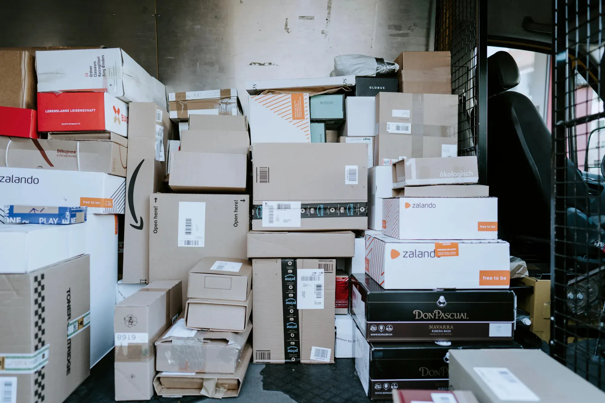 Interior de una camioneta de reparto con cajas de cartón apiladas hasta el techo